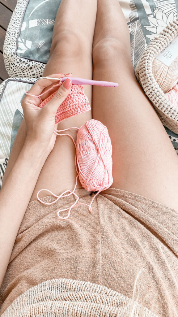 Joelyne holding spools of light pink, DK weight cotton yarn used for her made to measure crochet shorts project